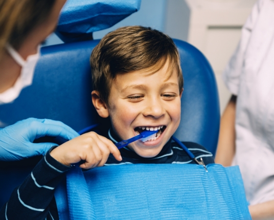 Child learning how to properly brush teeth from pediatric dentist