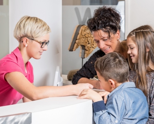 Dental patient and parents helped by dentistry team member to file a dental insurance claim