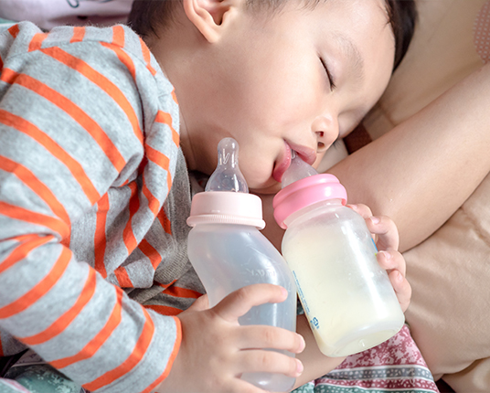 Baby falling asleep holding a bottle