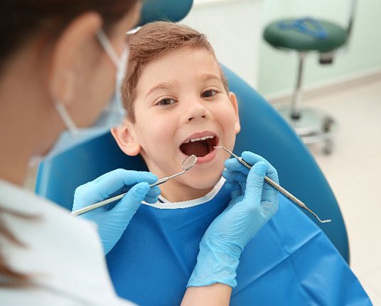 Child smiling while dentist examines their teeth and gums