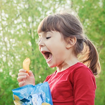 Excited child eating bag of chips outside