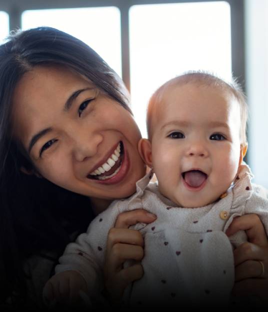 Mother holding laughing baby after lip and tongue tie release