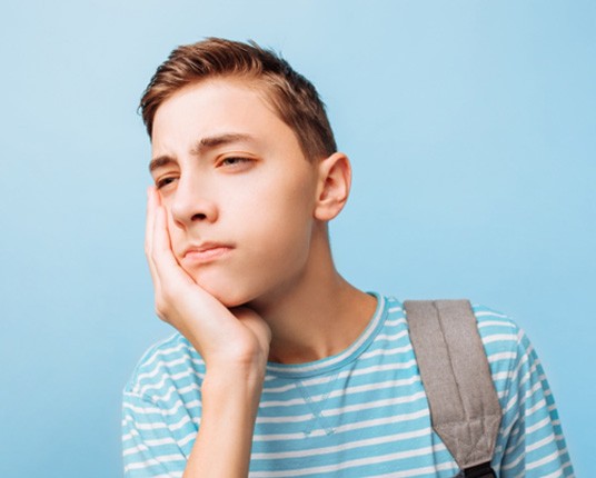 teen experiencing jaw pain due to wisdom teeth