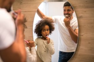 a father and daughter having fun while brushing their teeth