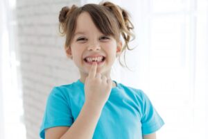 Child pointing to lost tooth.